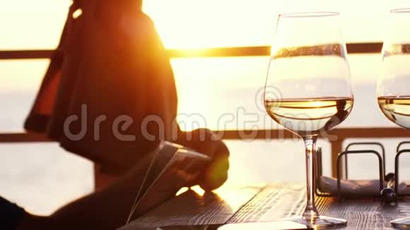 有菜单的人在海滩咖啡馆休息在日落背景下在海边慢动作地拿着玻璃镜头耀斑效应视频的预览图