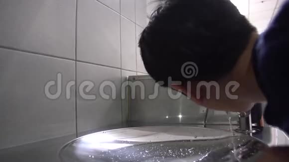 亚洲饥饿的男孩从水管里喝水视频的预览图