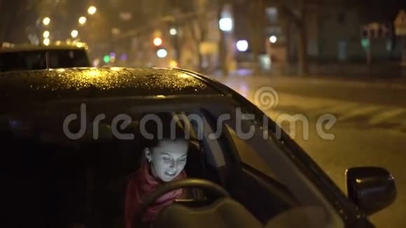 女士坐在黑色的车里在雨夜用平板电脑4K视频的预览图