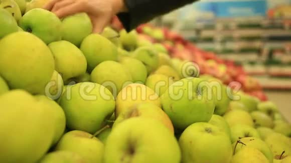 一个女人在蔬菜货架上的超市里买蔬菜和水果男人选择苹果视频的预览图