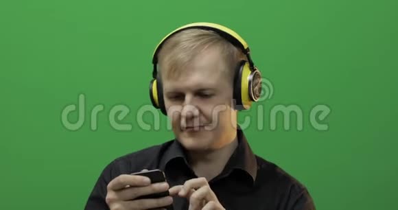 男人用无线黄色耳机听音乐跳舞绿色屏幕视频的预览图