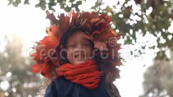 秋枫叶花圈冠上幸福微笑可爱小女孩的特写视频的预览图