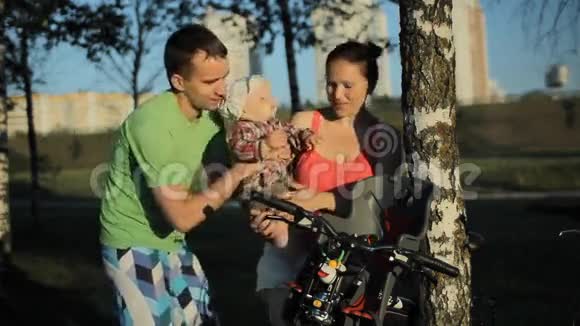一个漂亮的小男孩的父母坐在自行车公园的椅子上视频的预览图