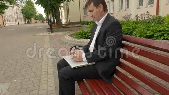 在街上坐在长椅上的商人用手机发微博视频的预览图