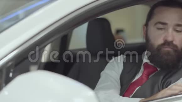 这幅画中有着迷人的自信的留着胡须的人坐在车里检查从车里买的新车视频的预览图