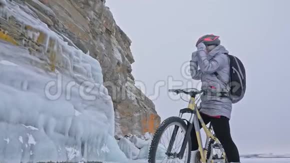 女人在冰上骑自行车女孩穿着银色羽绒服自行车背包和头盔女人是视频的预览图