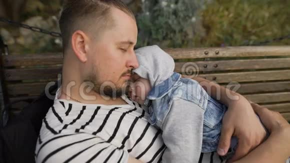 爸爸和小儿子在公园的长凳上休息视频的预览图