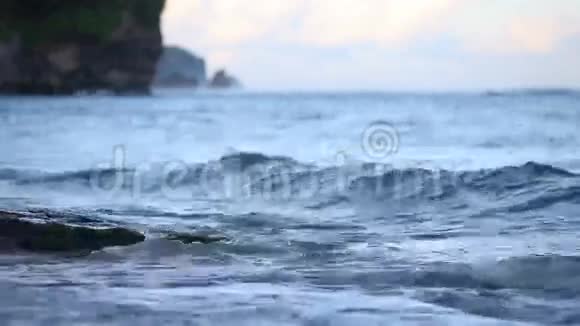 日落时分小海浪冲刷着海滩上的岩石视频的预览图