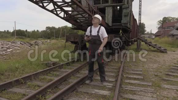 铁路员工在旧铁路机械附近打电话视频的预览图