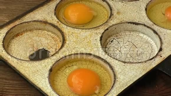 老式重型钢制煎锅中的鸡蛋在木制背景上隔离视频的预览图