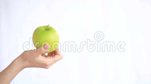 女人的手在白色的背景上拿着一个绿色的苹果视频的预览图