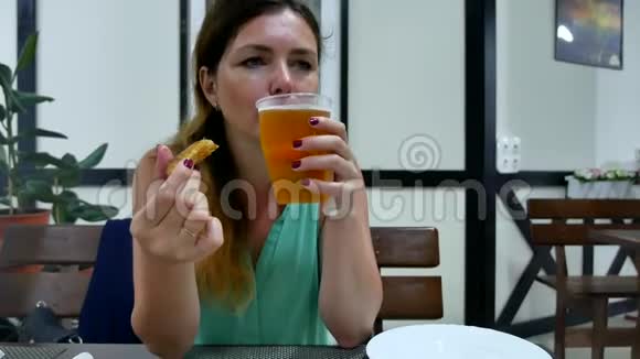 女孩在酒吧里喝啤酒女人喝啤酒吃鱼休息视频的预览图