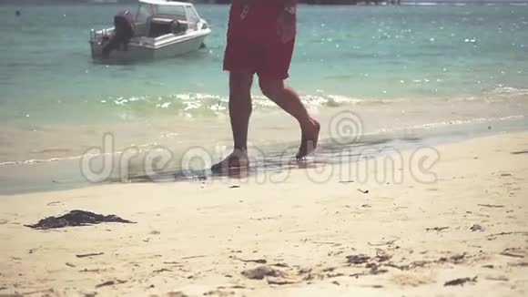 男性脚在金色沙滩上行走的特写镜头暑假假期慢动作视频的预览图