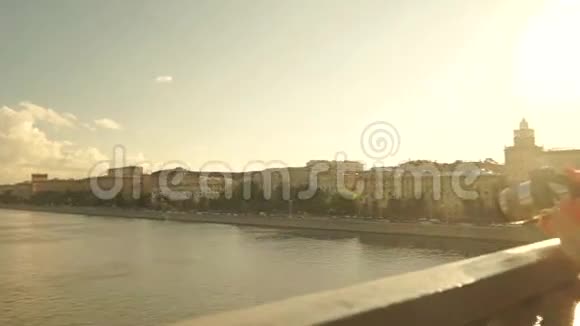 美丽的黑发女孩穿着粉红色的裙子从桥上拍摄日落照片慢动作安定夹视频的预览图