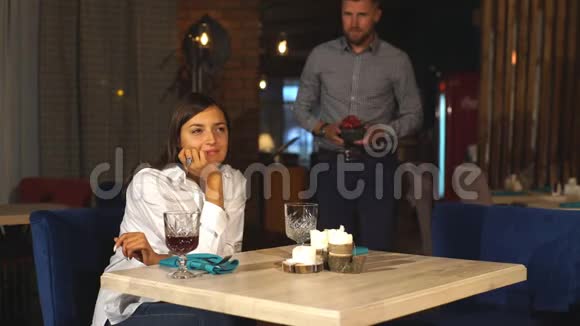 漂亮的年轻女人坐在咖啡馆里从男朋友那里得到一个礼品盒视频的预览图