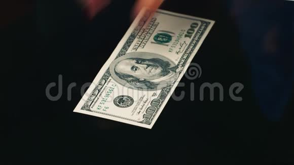 手在桌子上摊开一百美元的钞票视频的预览图