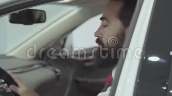 这幅画很吸引人有自信留着胡子的商人坐在车里检查从车里买的新车视频的预览图