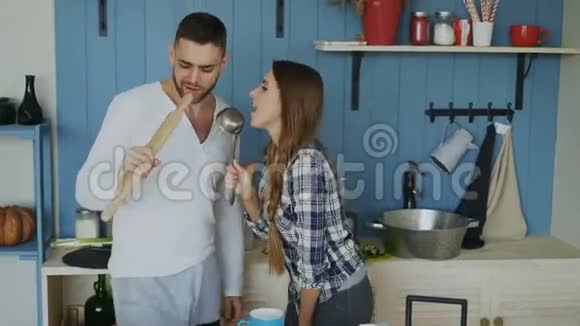 年轻快乐的一对夫妇在家里的厨房里摆好桌子吃早餐一边跳舞唱歌玩得很开心视频的预览图