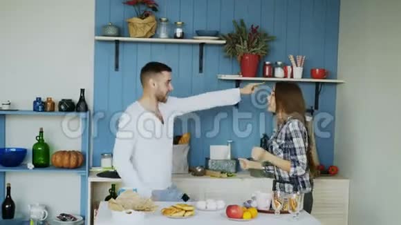 年轻快乐的一对夫妇在家里的厨房里摆好桌子吃早餐一边跳舞唱歌玩得很开心视频的预览图