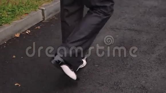 沥青路面黑色衬皮鞋帮男脚视频的预览图