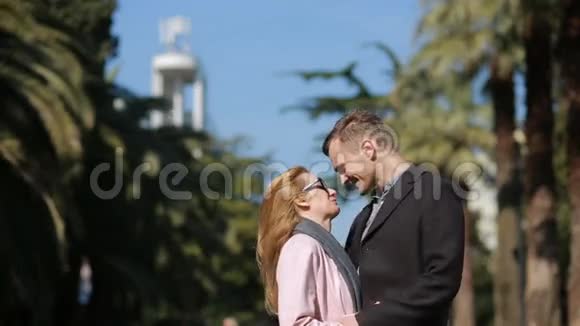 快乐的一对相爱的夫妇玩得很开心可爱的漂亮女人和一个穿外套的英俊男人接吻在这样的背景下视频的预览图