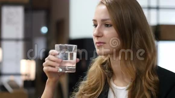 玻璃中的饮用水女孩坐在室内视频的预览图