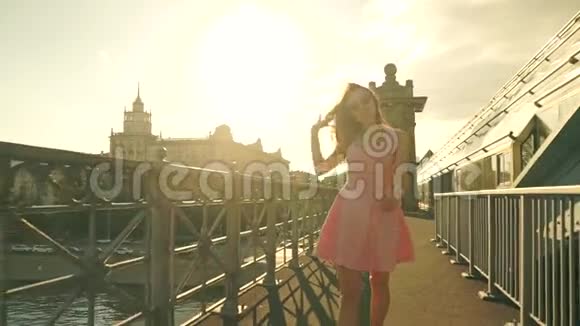 苗条的黑发女孩穿着粉红色的裙子在桥上散步慢动作安定夹视频的预览图