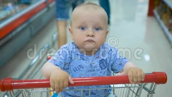 小婴儿坐在超市的购物车里而他的父亲选择购买视频的预览图