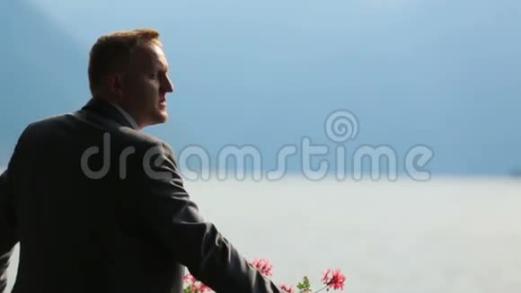 英俊的新郎观看意大利科莫湖美景的肖像视频的预览图