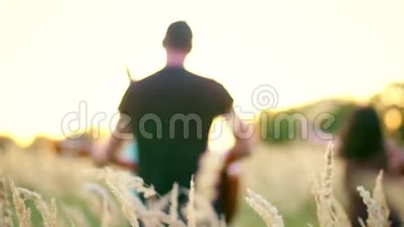 美丽的女孩和男孩在田野里散步日落时的尖峰视频的预览图