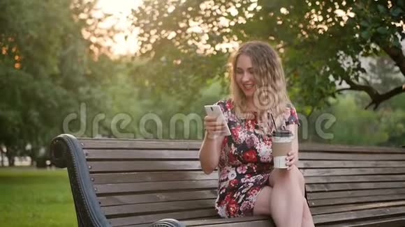 白人迷人的年轻卷发女人在智能手机上写短信手里拿着咖啡慢动作视频的预览图
