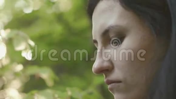 在森林里阳光明媚的夏日一个严肃而悲伤的黑发女人在阳光下注视着前方视频的预览图