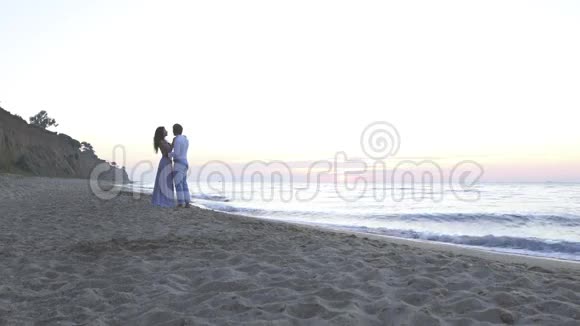 迷人的深爱的年轻夫妇晚上在海滩上接吻浪漫蜜月概念视频的预览图