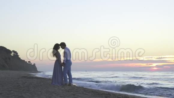 迷人的深爱的年轻夫妇晚上在海滩上有一个甜蜜的浪漫时刻浪漫蜜月概念视频的预览图