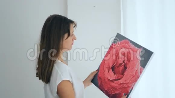 在墙上挂画的年轻女子视频的预览图