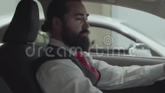 肖像画吸引人的成功留胡子的商人坐在车里检查从车买的汽车视频的预览图