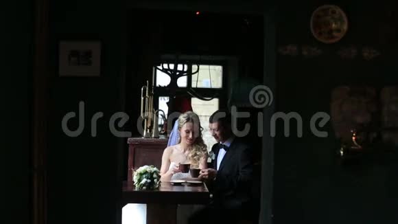 快乐迷人的新娘和新郎在黑暗中的咖啡馆喝咖啡视频的预览图