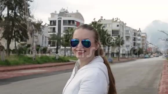 戴墨镜的漂亮女孩站在街上视频的预览图