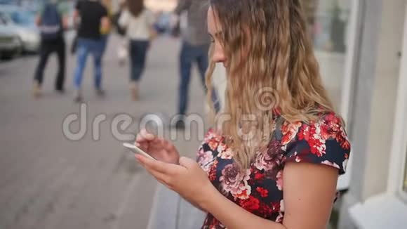 白人迷人的年轻卷发女人在智能手机上写短信手里拿着咖啡慢动作视频的预览图