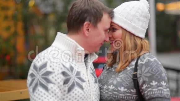 快乐的年轻夫妇在圣诞博览会上有乐趣情侣在爱亲吻户外圣诞快乐新年快乐视频的预览图