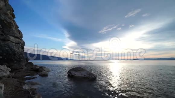 日出穿过背景水和天空的岩石视频的预览图