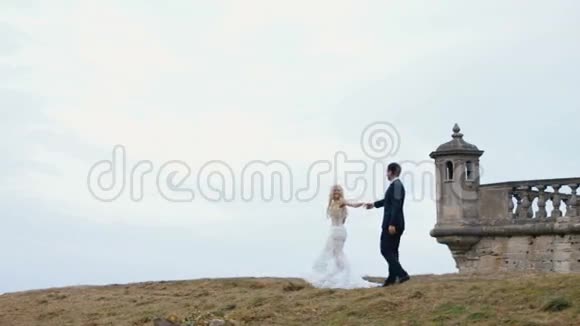 美丽的年轻新娘和新郎走在中世纪城堡的户外视频的预览图