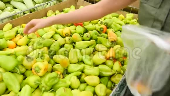 一个女人在蔬菜货架上的超市里买蔬菜和水果男人选择胡椒保加利亚慢动作4k视频的预览图