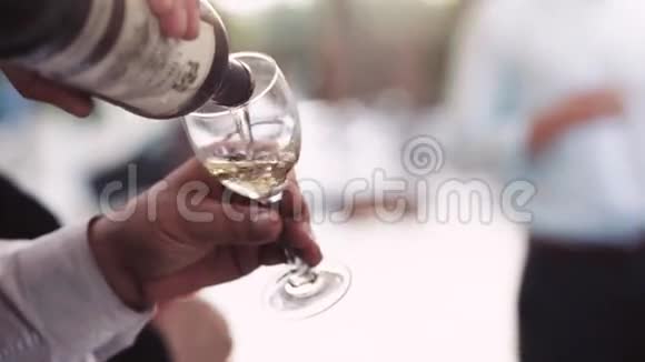 玛娜手把白葡萄酒倒进酒杯里婚礼派对意大利婚礼近景慢动作户外活动视频的预览图