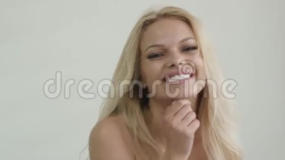 一个皮肤黝黑迷人的金发女孩对着镜头微笑的特写镜头视频的预览图
