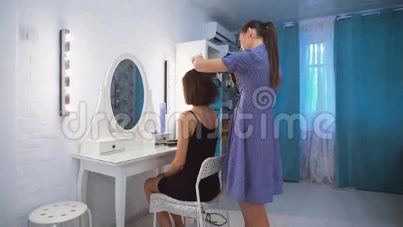 时尚的专业人士你可以信任美发师用吹风机给客户做头发背景是视频的预览图