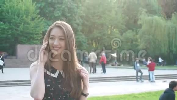 绿泉公园里一位长着一头乌黑长发的迷人年轻女士在电话里微笑着视频的预览图