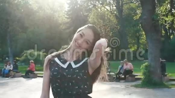 年轻时尚的黑发女人在公园的绿色小巷里微笑视频的预览图