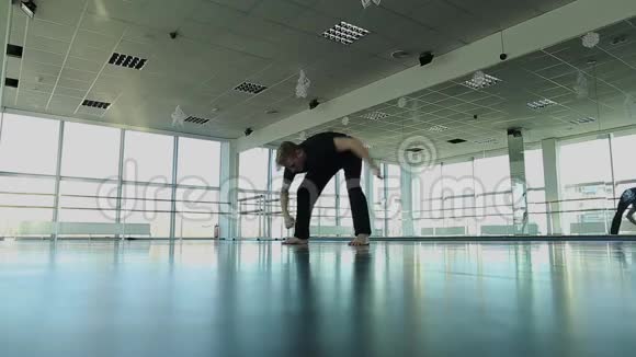 穿着黑色西装的金发舞者在健身房锻炼视频的预览图