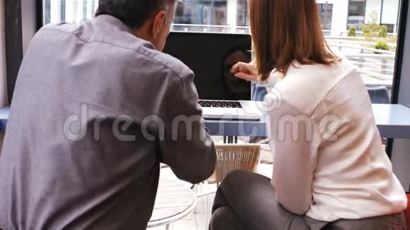 商务人士一边喝咖啡一边讨论笔记本电脑视频的预览图